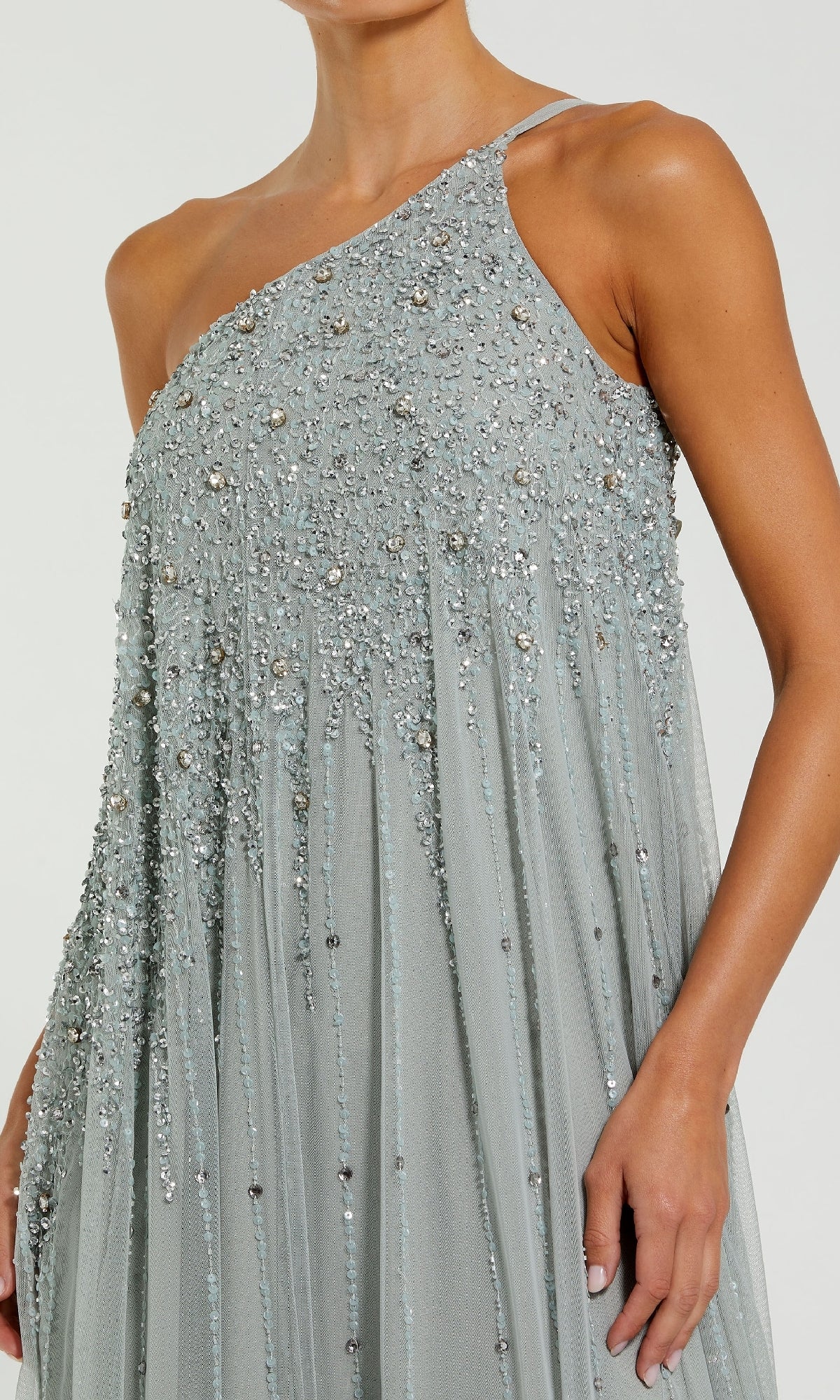 A woman wears the Mac Duggal 9224, a light grey one-shoulder long formal dress adorned with silver sequins and beadwork—ideal for special occasions.